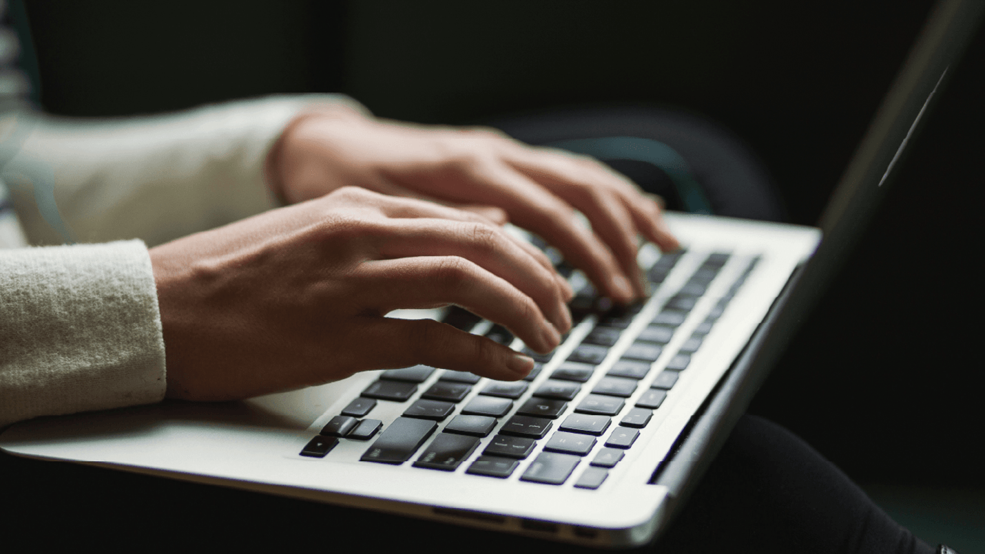 Close up of hands typing on a laptop keyboard