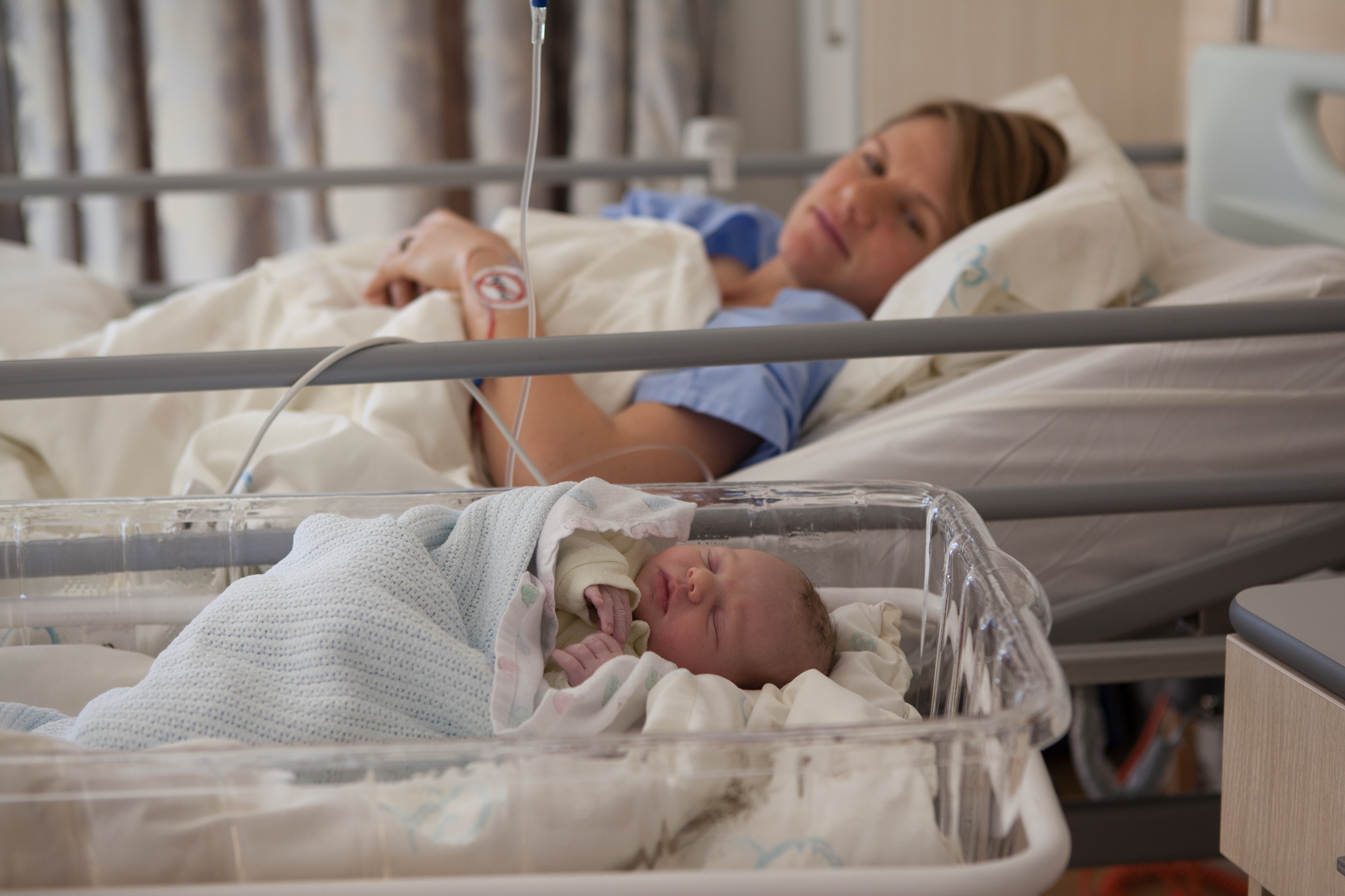 Women in bed and baby in bassinet in Hospital
